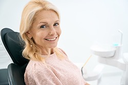 Female patient in pink shirt sitting back in dental chair