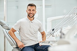 Man in white shirt sitting in dental chair smiling