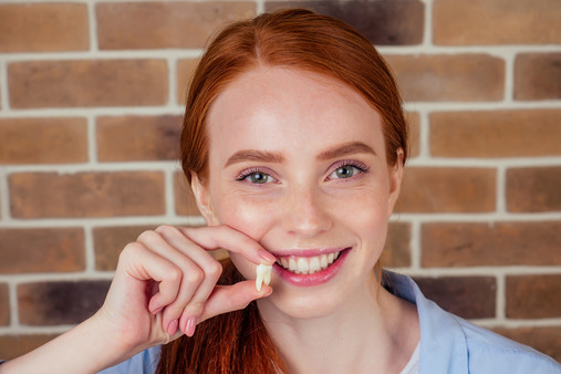 young woman holding extracted tooth 